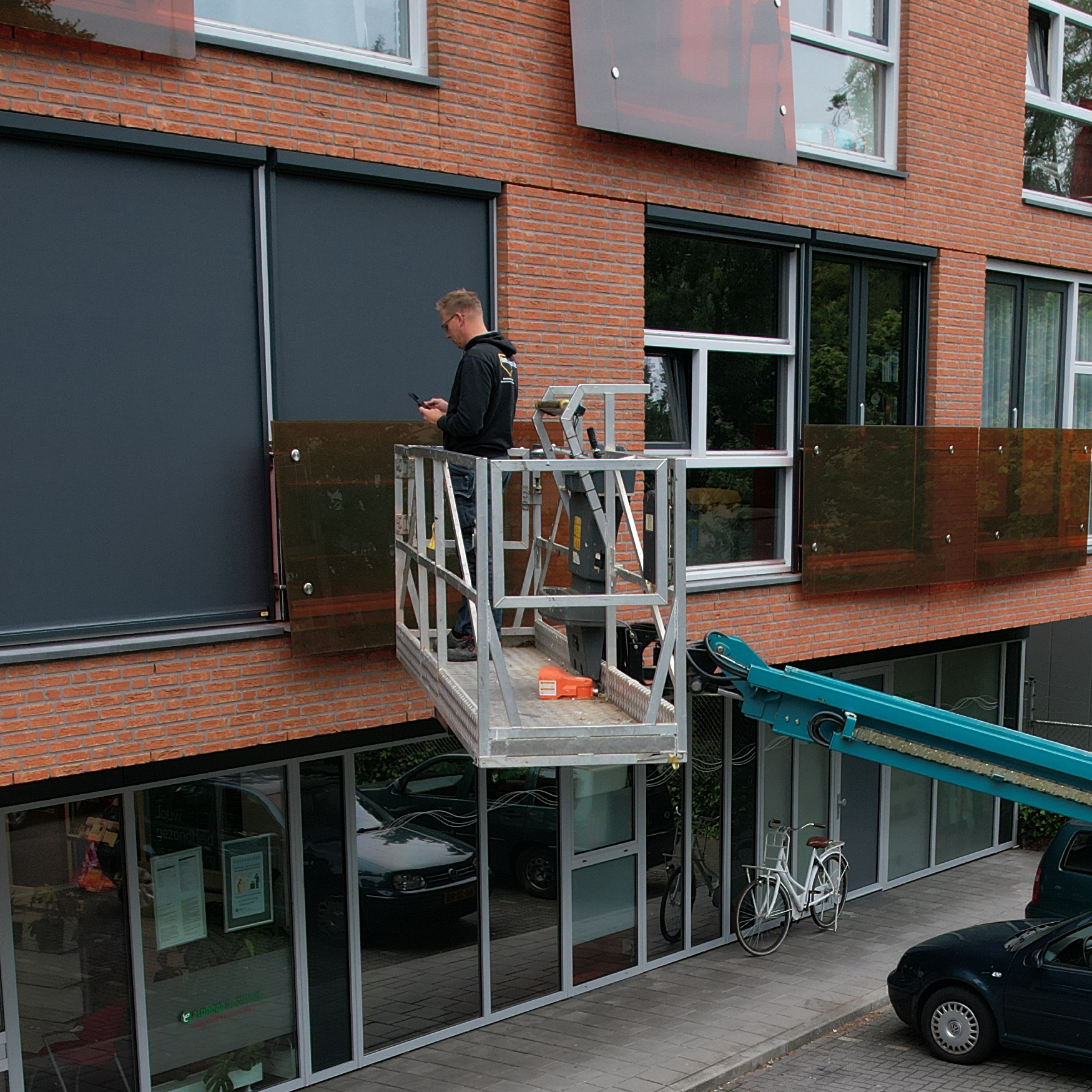 Monteur van Zon & Window Styling installeert screens met hoogwerker